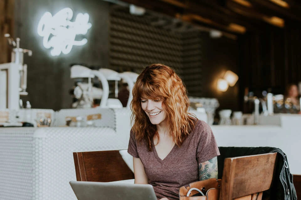 Femme souriante travaillant sur son ordinateur portable dans un café chaleureux